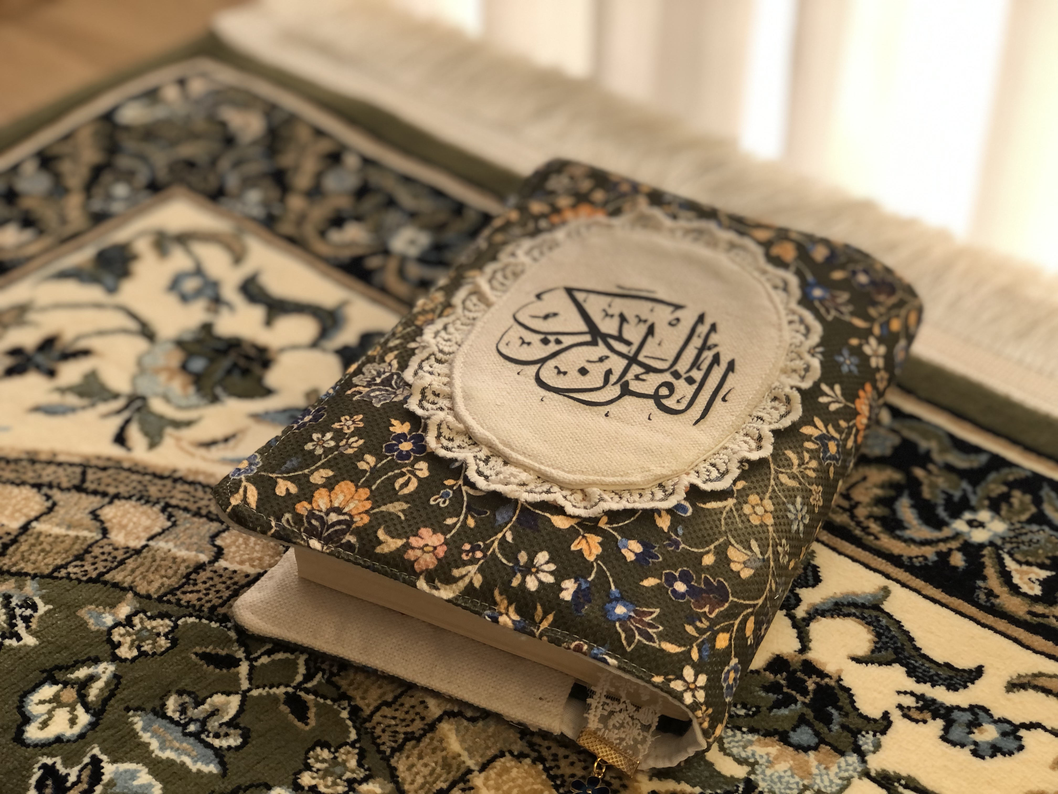 Rawda Quran cover in a dark green floral fabric with Arabic calligraphy detail
